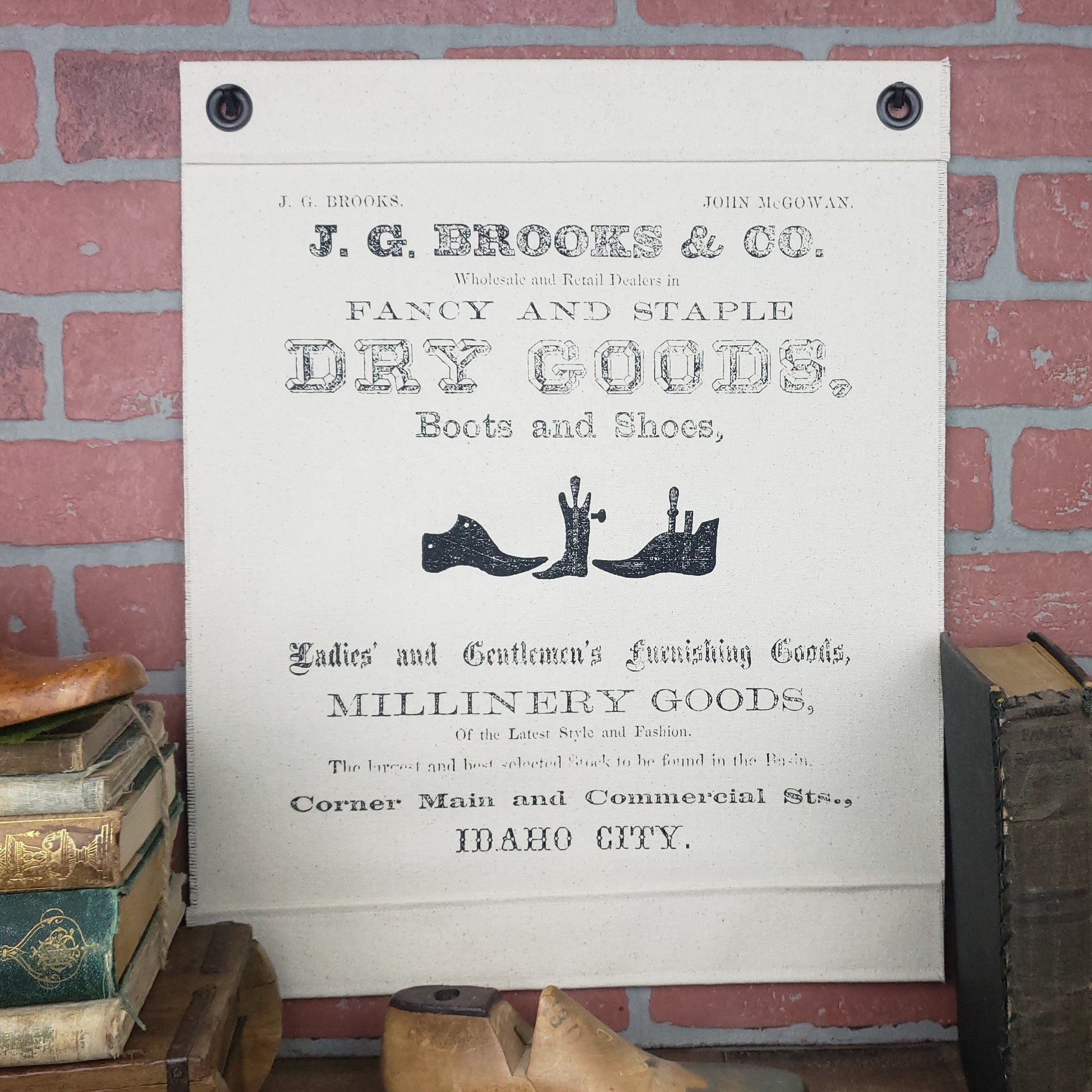 Vintage image of a Brooks & McGowan Dry Goods newspaper ad c.1862, Idaho City. Screen printed on our Inked Canvas wall hanging, wall decor, or wall art. Hand made in the USA by Heart in Hand Mercantile using natural, unbleached 100% Cotton Heavy Duck Canvas and hung by two grommets.